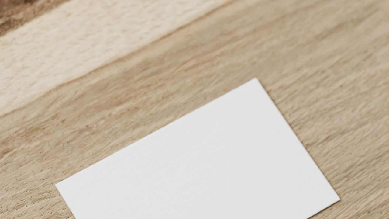 Schlichte weiße Visitenkarte auf einem Holzschreibtisch