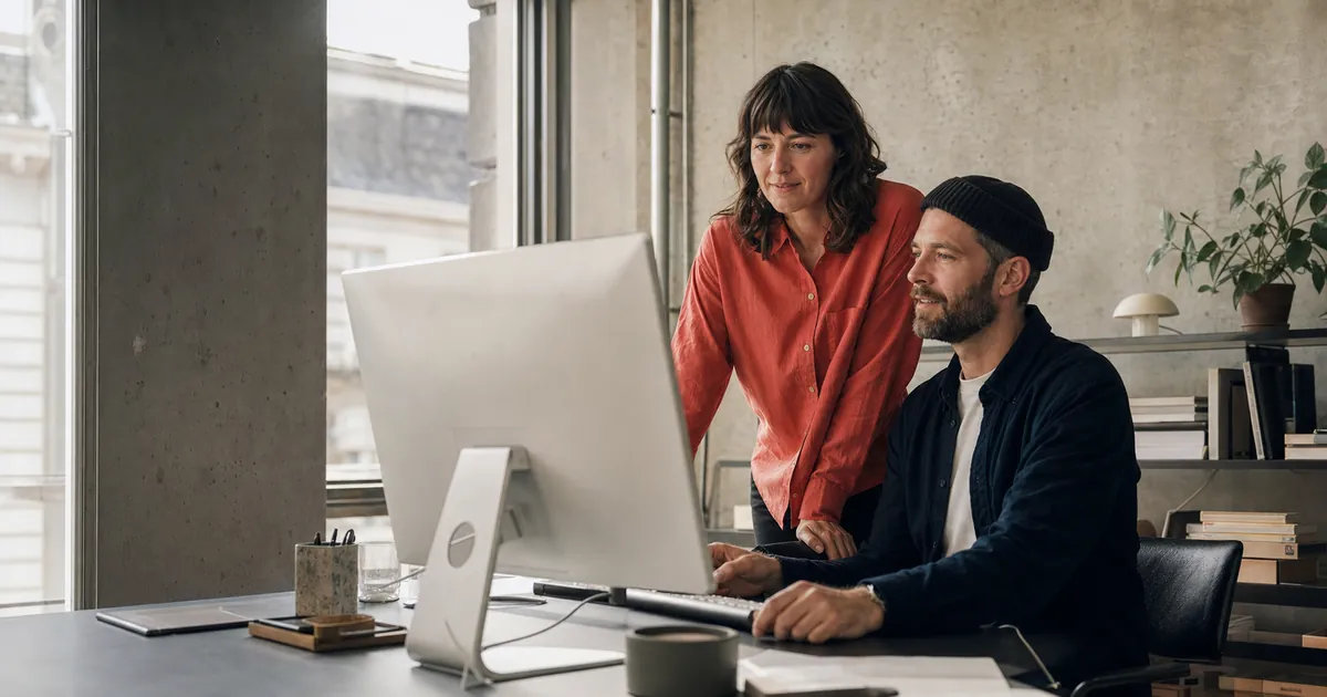 Unternehmerin und Webdesigner besprechen gemeinsam ein Website-Projekt in einem Berliner Studio