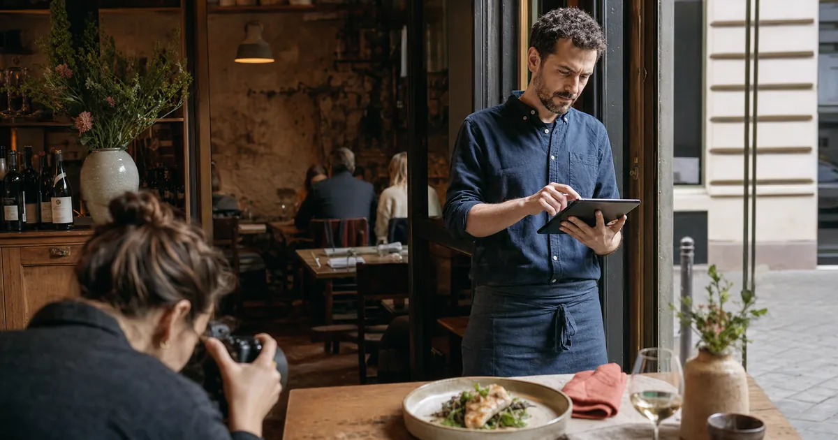 Berliner Gastronom prüft seine digitale Speisekarte während professionelle Restaurantfotos entstehen